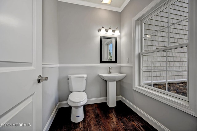 bathroom with wood finished floors, baseboards, a sink, crown molding, and toilet