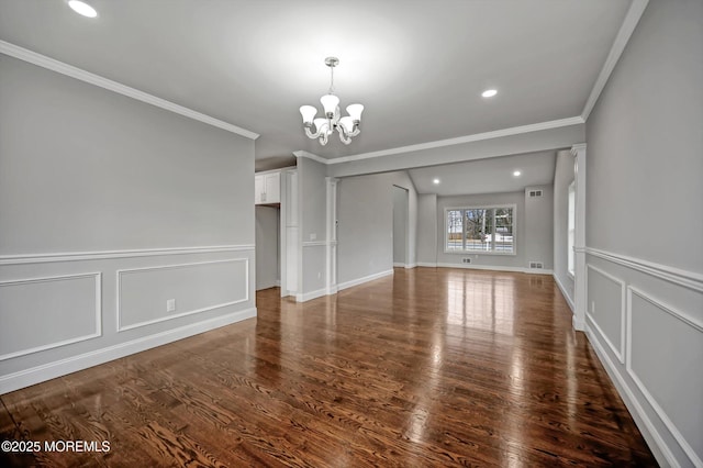 interior space featuring a notable chandelier, wood finished floors, crown molding, and a decorative wall