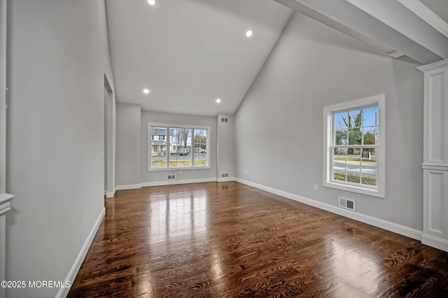 unfurnished room with visible vents, plenty of natural light, baseboards, and wood finished floors