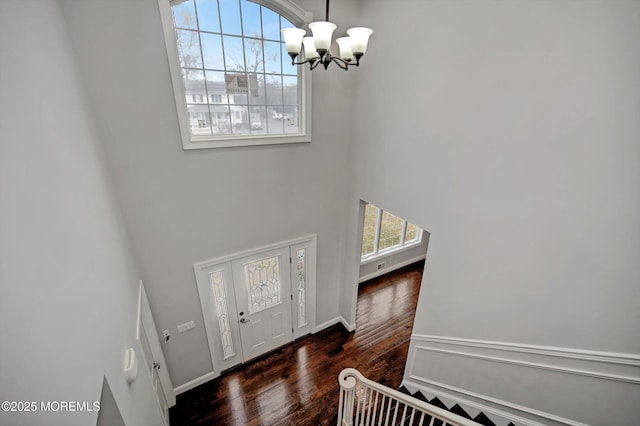 foyer featuring a high ceiling, an inviting chandelier, and wood finished floors