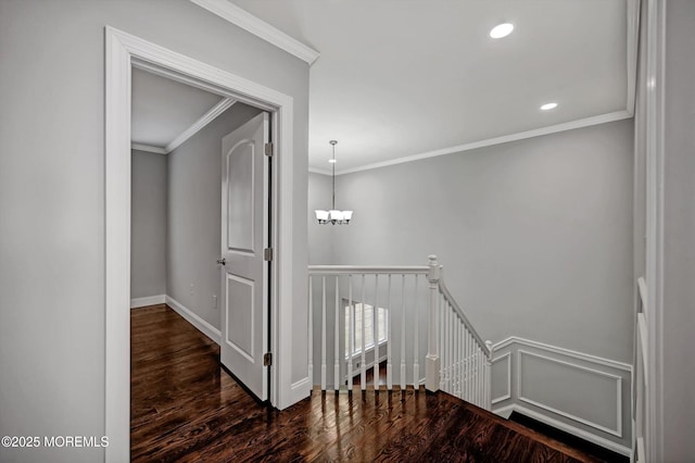 hall featuring an upstairs landing, a notable chandelier, wood finished floors, crown molding, and a decorative wall