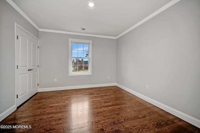 empty room featuring visible vents, baseboards, wood finished floors, and crown molding