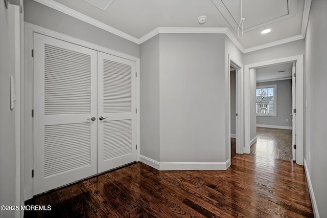 corridor featuring dark wood finished floors, attic access, crown molding, and baseboards