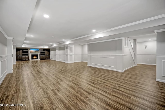 unfurnished living room featuring a decorative wall, recessed lighting, wood finished floors, and a lit fireplace