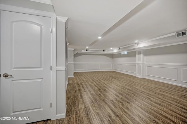 finished below grade area featuring visible vents, recessed lighting, a wainscoted wall, and wood finished floors