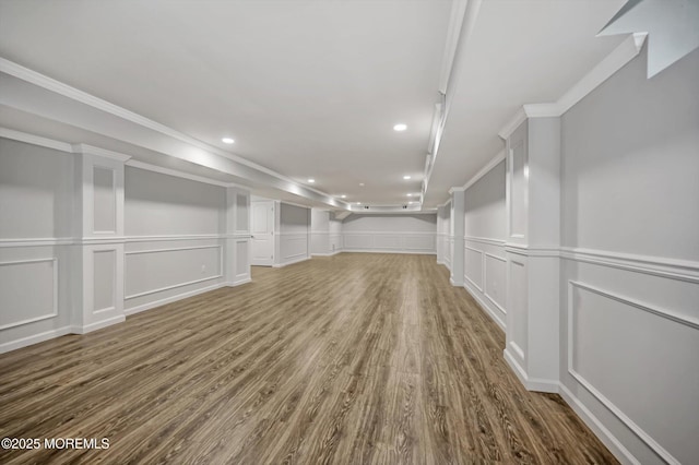 finished basement with a decorative wall, recessed lighting, wood finished floors, and ornamental molding