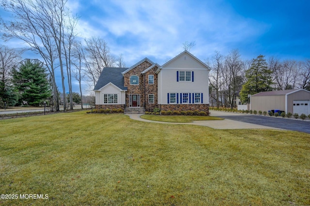 traditional-style home featuring stone siding, an outdoor structure, and a front yard