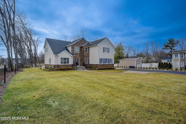 traditional-style house with stone siding, a front lawn, driveway, and fence