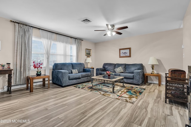 living room featuring ceiling fan, light wood-style flooring, baseboard heating, and visible vents