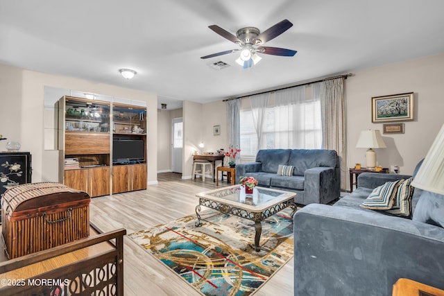 living area with light wood finished floors, baseboards, visible vents, and a ceiling fan