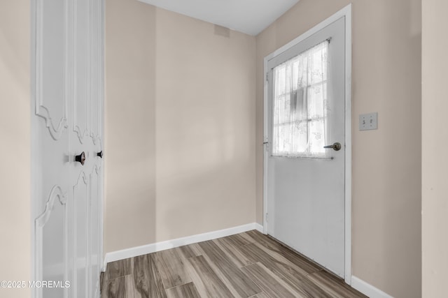 doorway with baseboards and wood finished floors