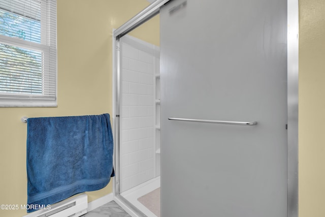 bathroom featuring marble finish floor, a stall shower, and a baseboard radiator