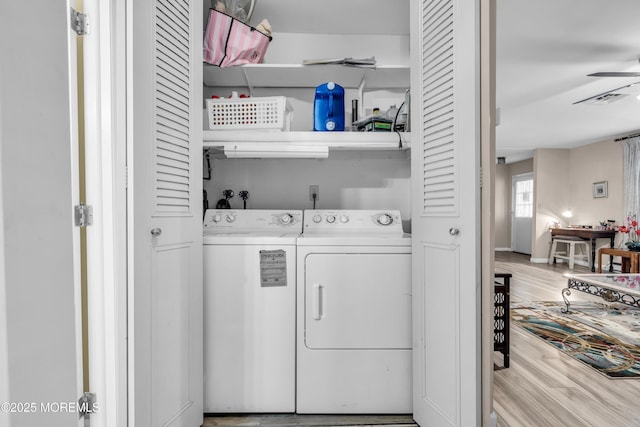 laundry room with laundry area, visible vents, a ceiling fan, wood finished floors, and washing machine and dryer