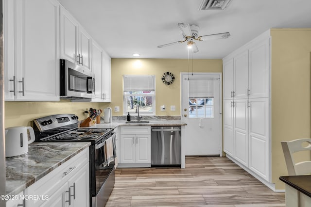 kitchen with white cabinetry, visible vents, stainless steel appliances, and a sink