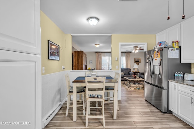 kitchen featuring light wood-style floors, white cabinetry, stainless steel refrigerator with ice dispenser, and baseboard heating