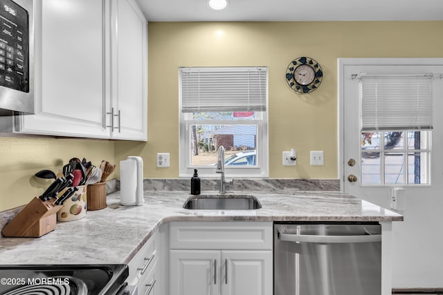 kitchen with a wealth of natural light, white cabinetry, appliances with stainless steel finishes, and a sink