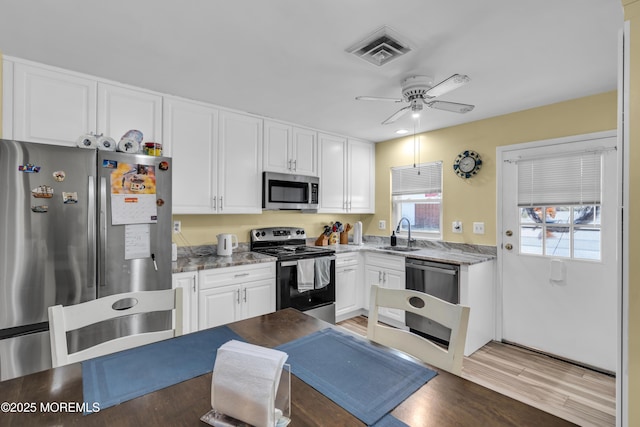 kitchen with visible vents, white cabinets, appliances with stainless steel finishes, light wood-type flooring, and a sink