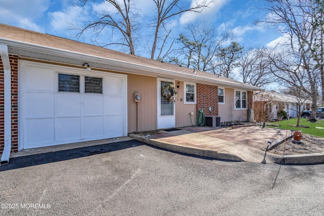 ranch-style house featuring an attached garage and aphalt driveway