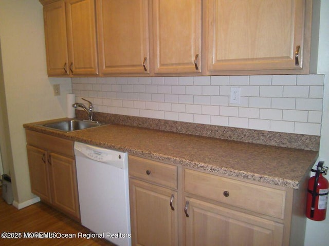 kitchen with white dishwasher, decorative backsplash, a sink, and wood finished floors