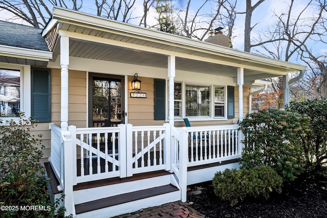 entrance to property with covered porch, roof with shingles, and a chimney