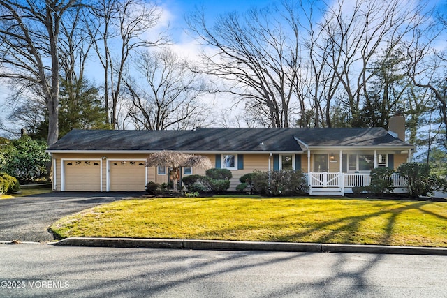 ranch-style house featuring an attached garage, covered porch, driveway, a chimney, and a front yard