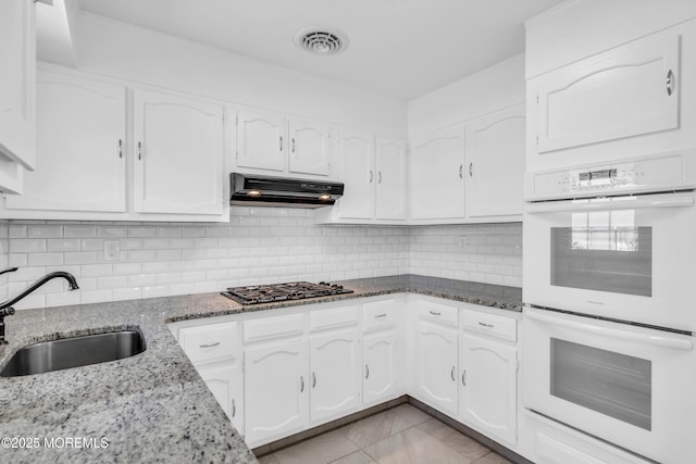 kitchen featuring visible vents, white double oven, under cabinet range hood, gas cooktop, and a sink