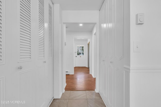 hallway with light tile patterned floors and baseboard heating