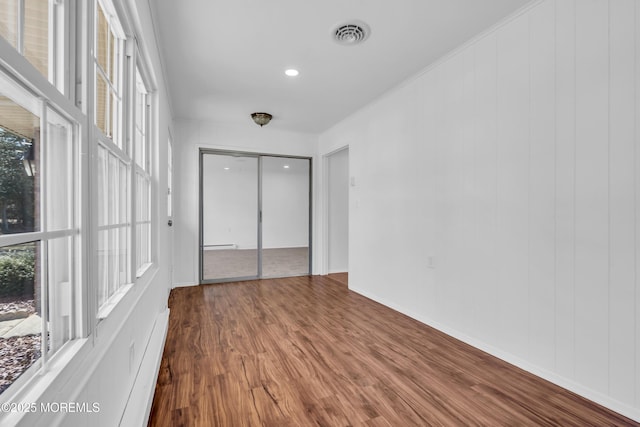 unfurnished bedroom featuring visible vents, multiple windows, baseboards, and wood finished floors