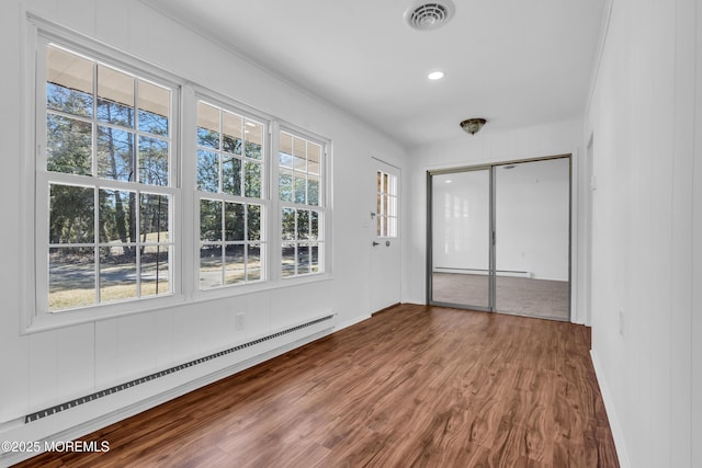 unfurnished bedroom with a closet, dark wood-style floors, visible vents, and baseboard heating