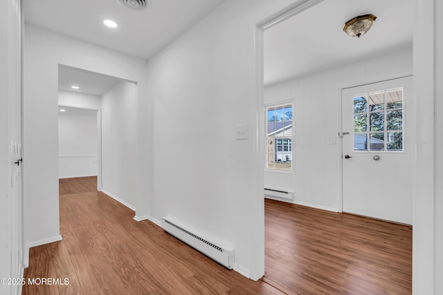 hall featuring visible vents, a baseboard heating unit, baseboards, wood finished floors, and a baseboard radiator