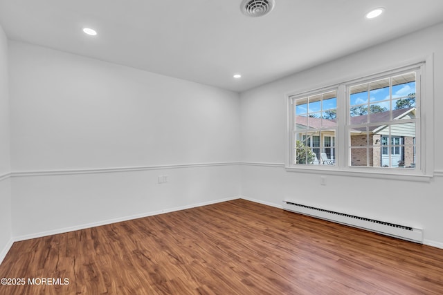 spare room with recessed lighting, a baseboard heating unit, visible vents, and wood finished floors