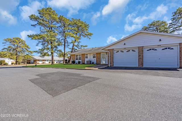 view of front of house featuring a garage, a front yard, brick siding, and driveway