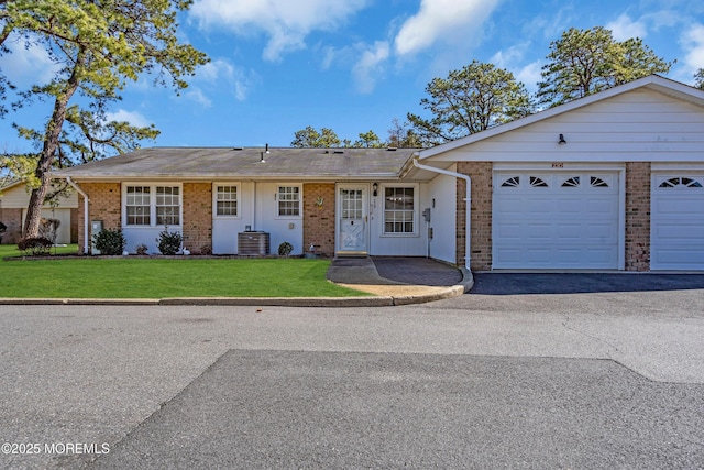 single story home featuring an attached garage, brick siding, central AC unit, and a front lawn