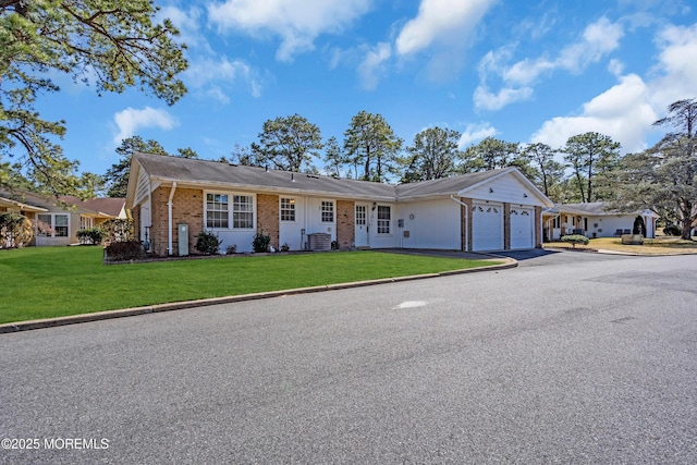 ranch-style house with a garage, brick siding, central AC unit, and a front lawn