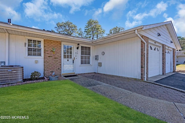 view of front facade featuring brick siding, a front lawn, aphalt driveway, central AC unit, and a garage