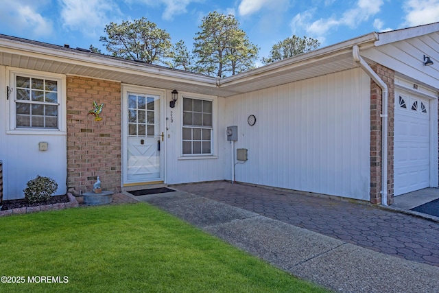 property entrance featuring brick siding, a lawn, and a garage