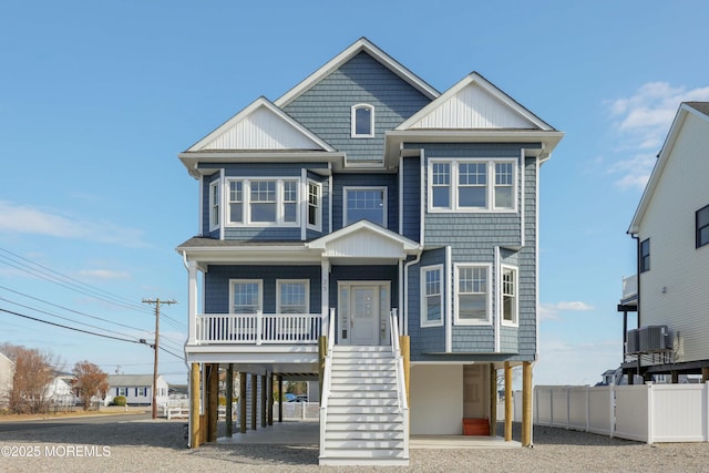 coastal home with a porch, stairway, fence, a carport, and driveway