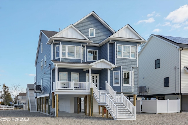 coastal inspired home with covered porch, stairway, fence, a carport, and driveway