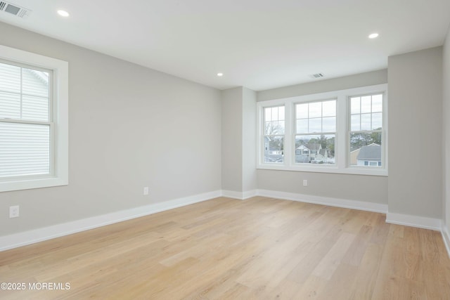 spare room with light wood-type flooring, baseboards, and visible vents