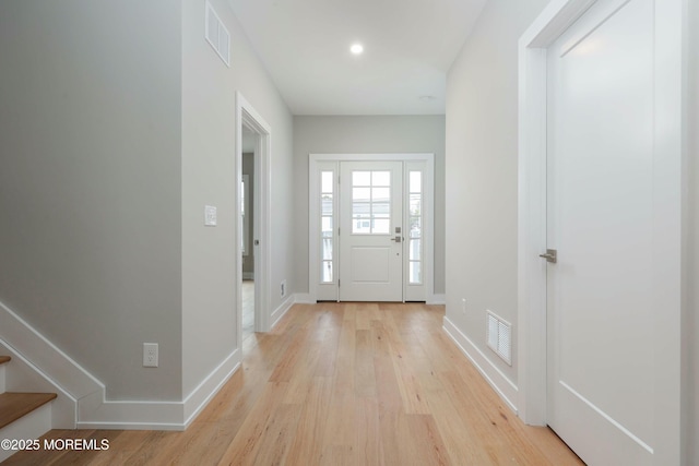 entrance foyer with light wood finished floors, stairway, visible vents, and baseboards