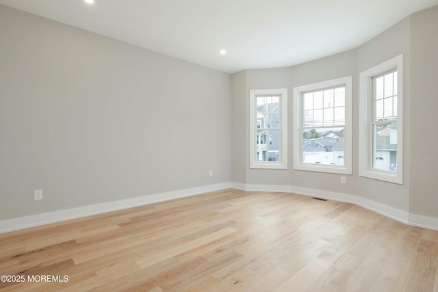 spare room featuring light wood-style floors, visible vents, baseboards, and recessed lighting