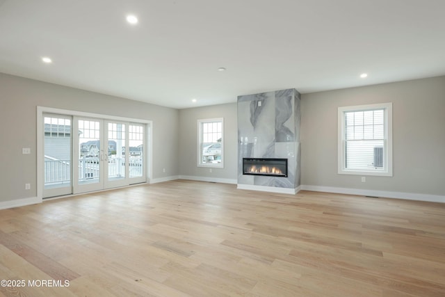 unfurnished living room featuring light wood-style floors, recessed lighting, and a high end fireplace