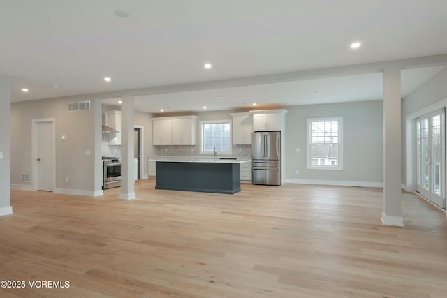 kitchen with visible vents, white cabinets, appliances with stainless steel finishes, open floor plan, and a center island