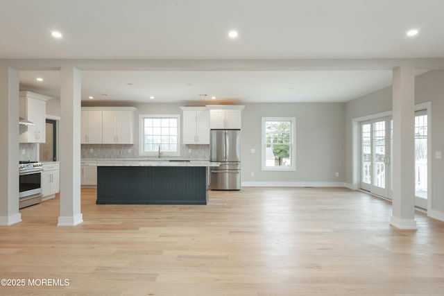 kitchen with decorative columns, appliances with stainless steel finishes, a kitchen island, and white cabinetry