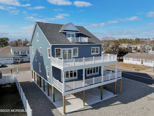 rear view of property featuring roof with shingles, a patio, a balcony, a fenced backyard, and driveway