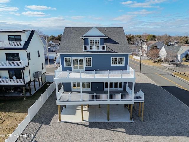 rear view of house with a balcony, a fenced backyard, a patio, and roof with shingles