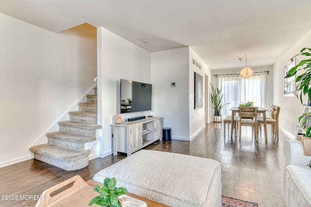 living room featuring stairs, visible vents, baseboards, and dark wood-style flooring