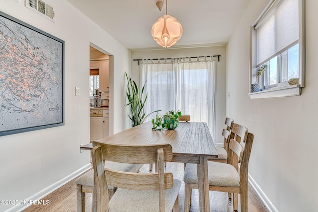 dining area with visible vents, baseboards, a healthy amount of sunlight, and wood finished floors