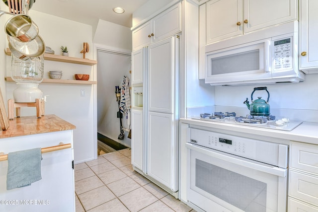 kitchen with light tile patterned flooring, white cabinets, white appliances, and light countertops