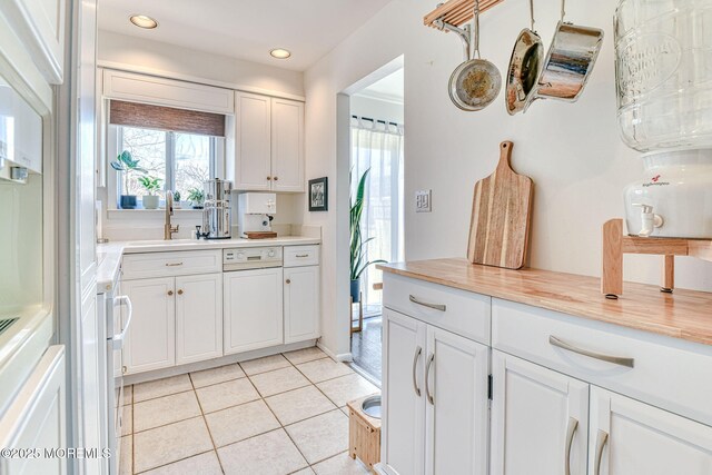 kitchen with light countertops, light tile patterned floors, recessed lighting, white cabinets, and a sink